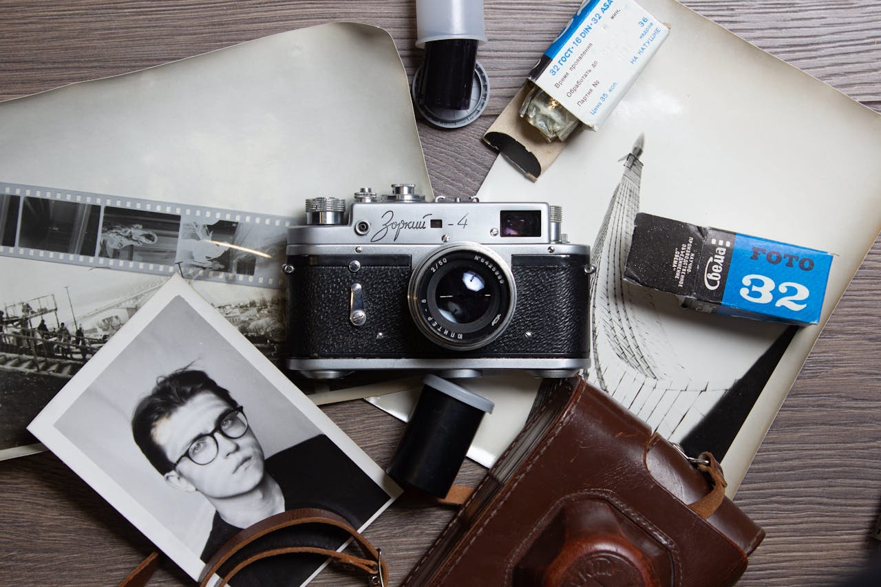 Flat lay of vintage camera, film rolls, and nostalgic photographs on a table.