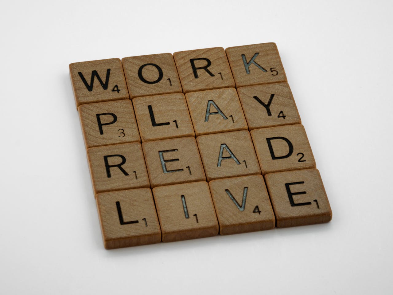 Wooden Scrabble tiles arranged to spell the words work, play, read, and live.